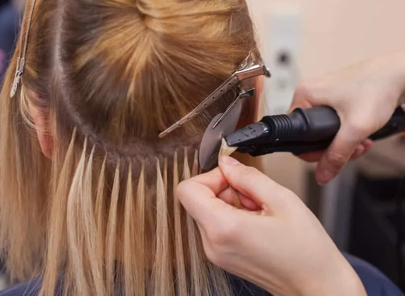 keratin fusion hair extensions being applied in a salon